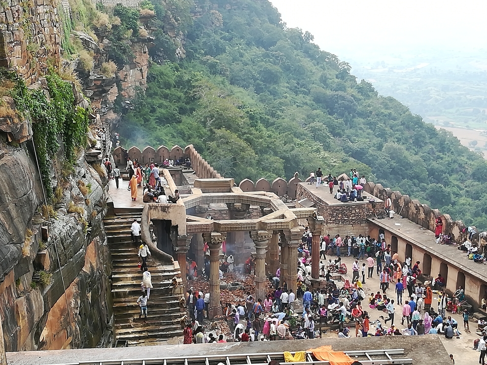 Large gathering of people at a temple on a mountain.