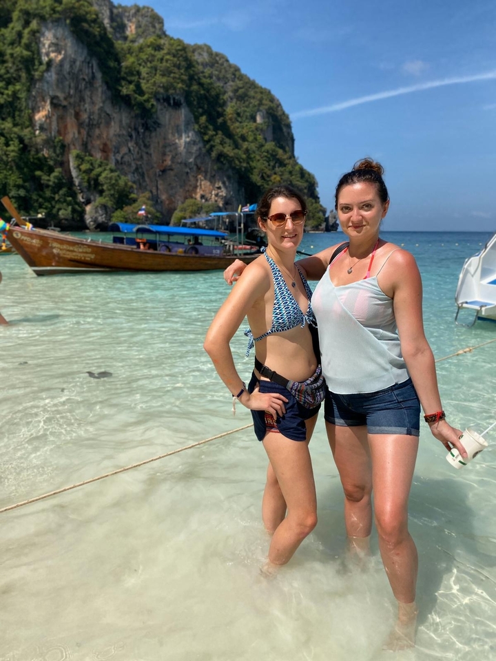 Two people posing on a beach with clear water.