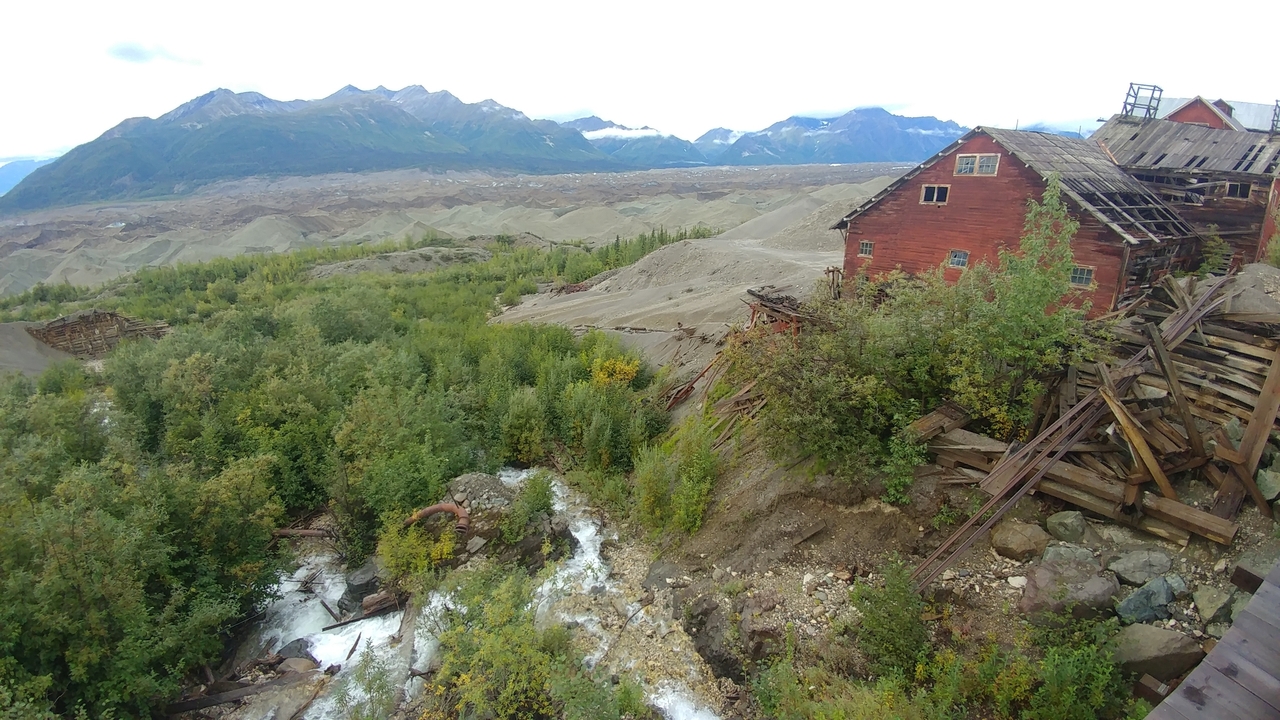 Panoramic view of a vast landscape with mountains and a wooden structure.