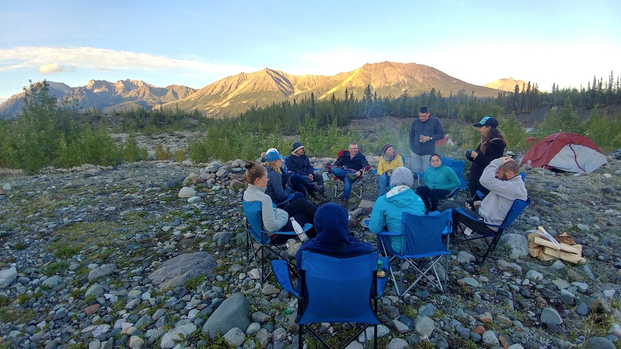 Group of people sitting outdoors in a circle, enjoying the scenery.