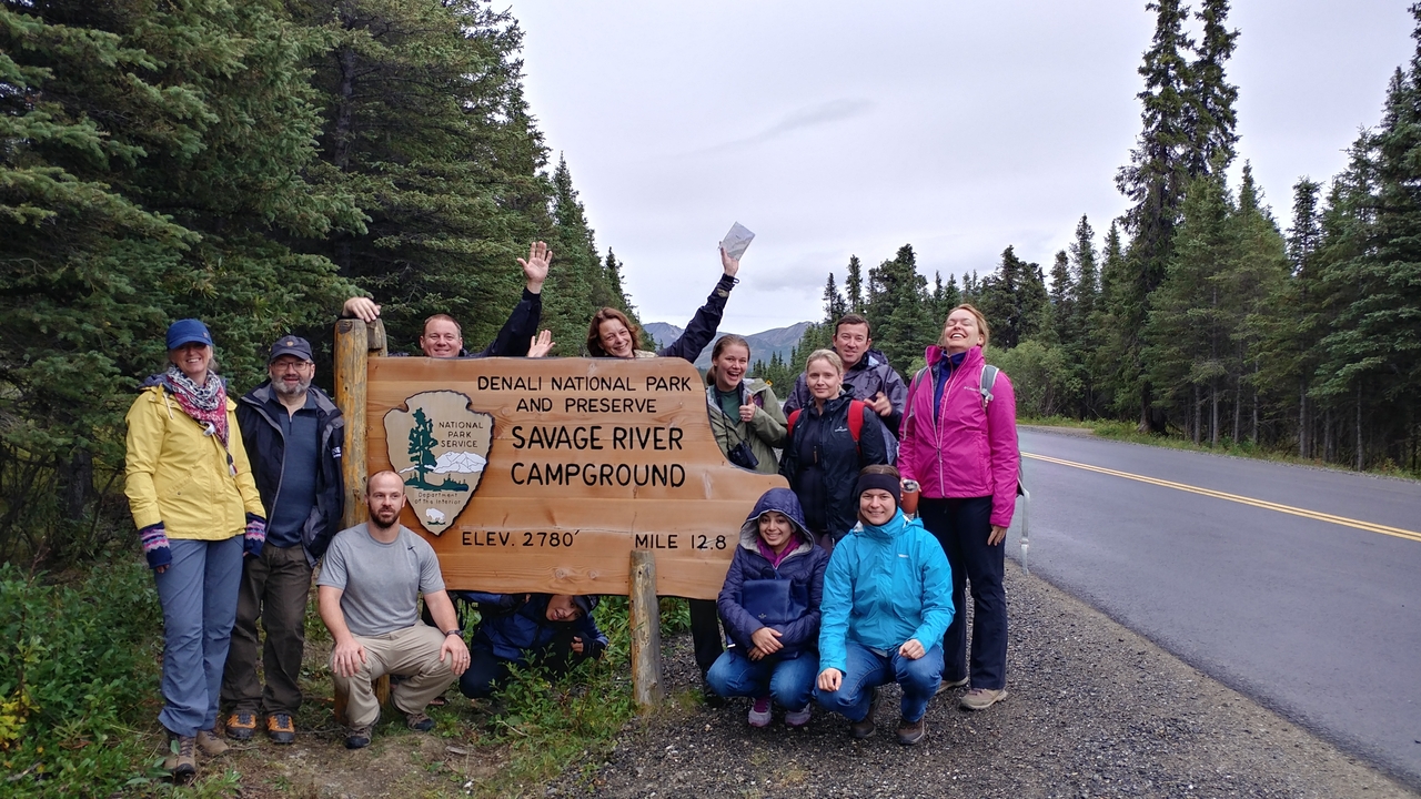 Group of people posing with a sign of Denali National Park.