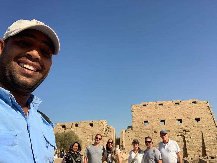 Person smiling with a historical structure behind.