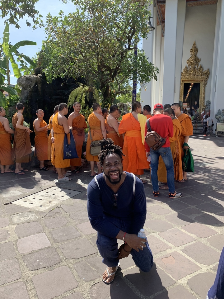 Man posing with monks dressed in orange robes.