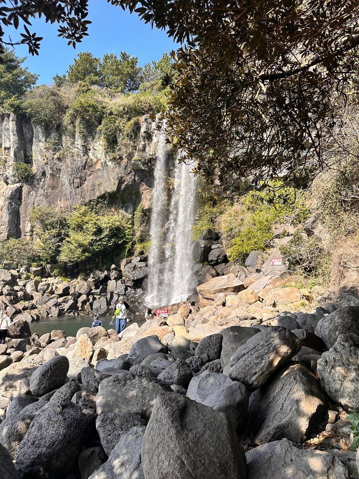 Cascade d'eau qui dégringole sur les rochers avec des gens à proximité.