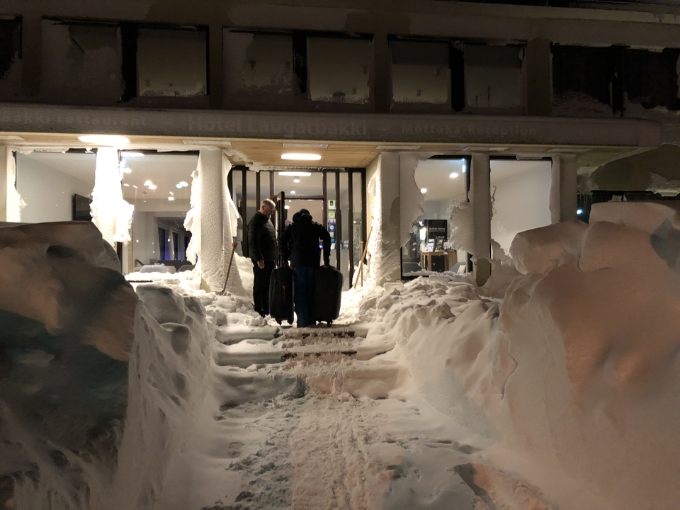 People entering a snowy hotel entrance.
