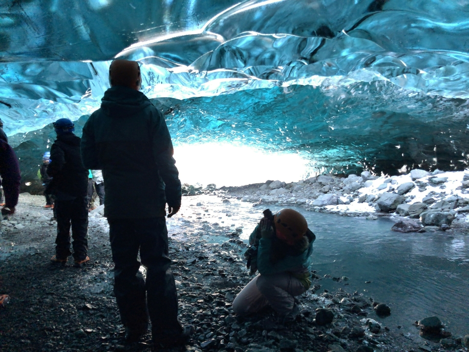 People inside an ice cave with blue ice formations.