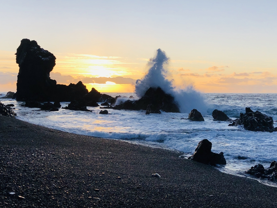 Waves crashing on rocks during sunset.