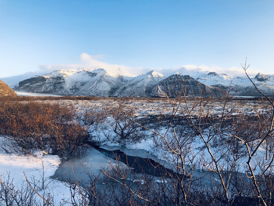 Mountain landscape with snow-covered peaks and a frozen river.