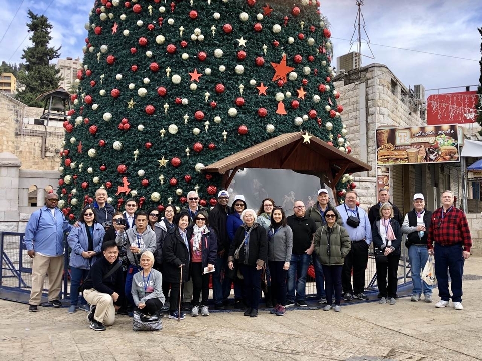 Photo de groupe devant un grand sapin de Noël extérieur.