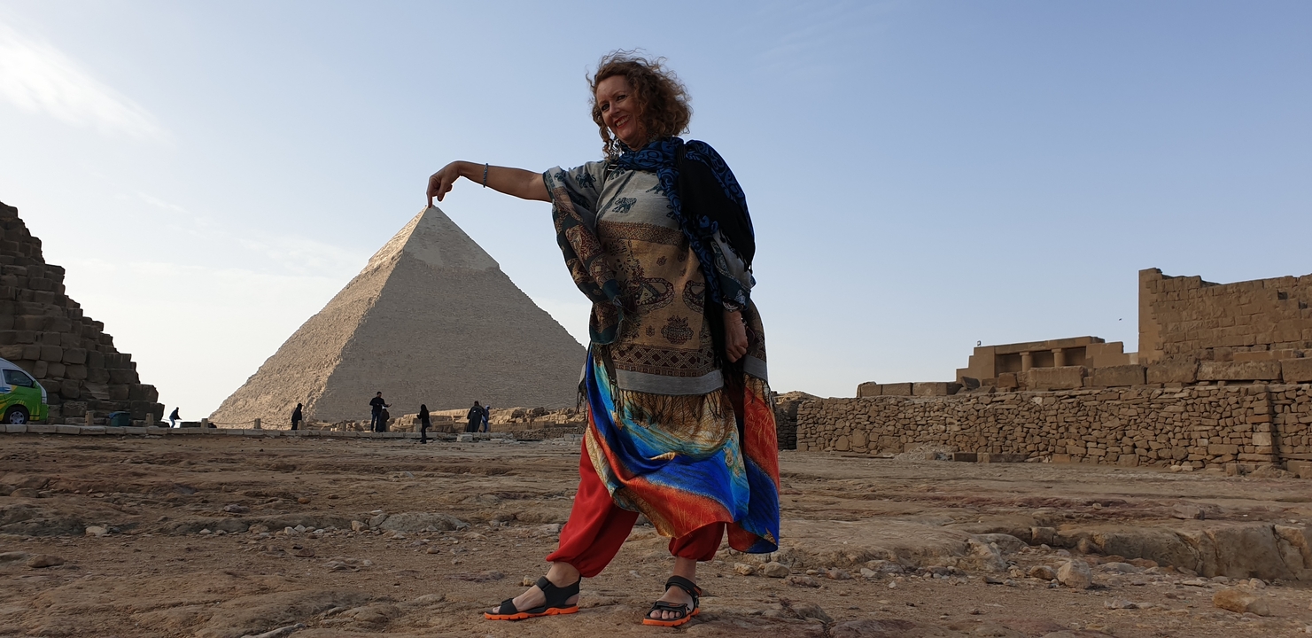 Woman mimicking holding the top of a pyramid from a distance.