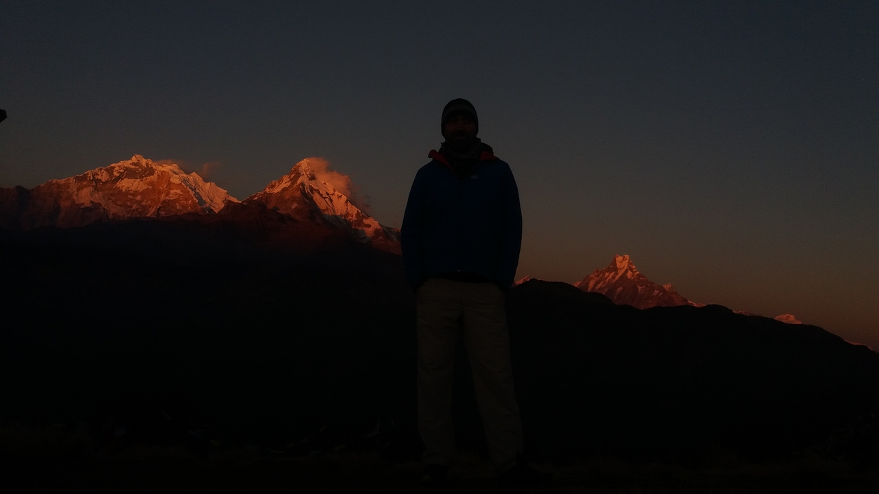 Silhouette d'une personne devant des montagnes au lever ou au coucher du soleil.