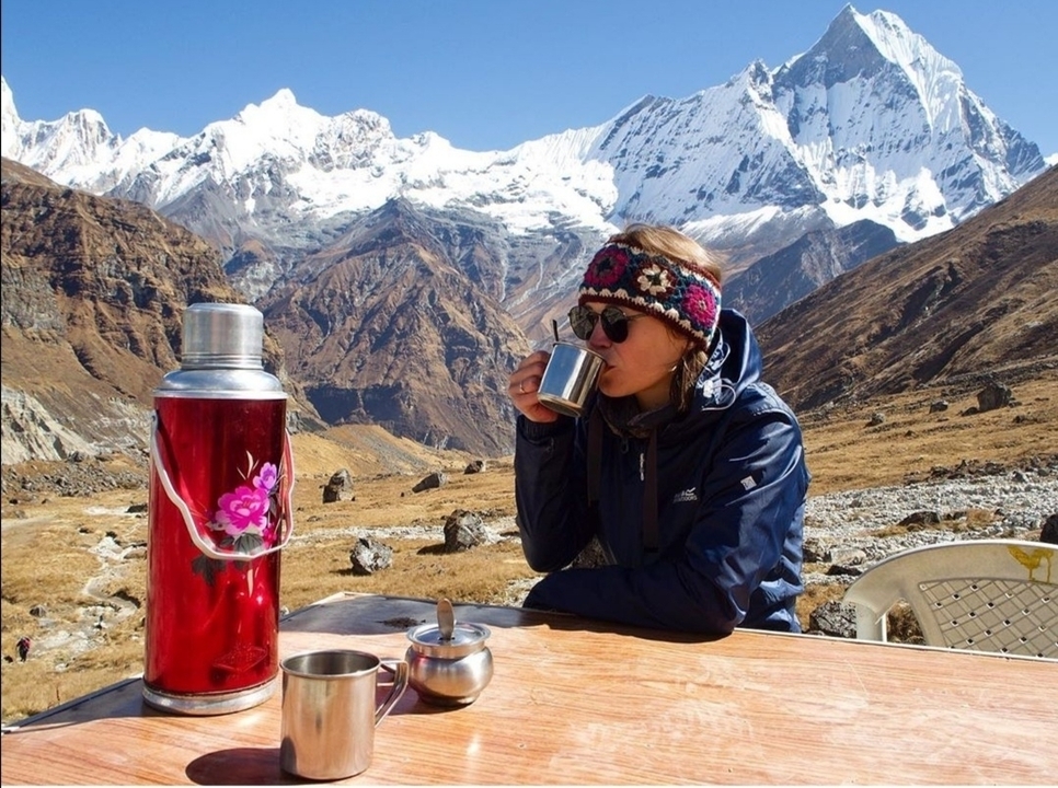 Personne savourant une boisson avec des montagnes enneigées en arrière-plan.