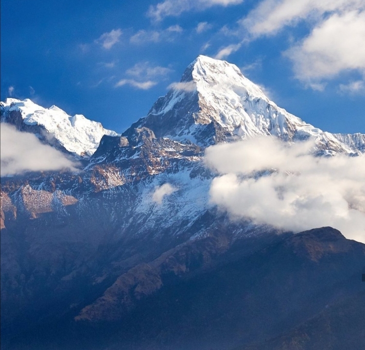 Sommet de montagne enneigé avec des nuages environnants.