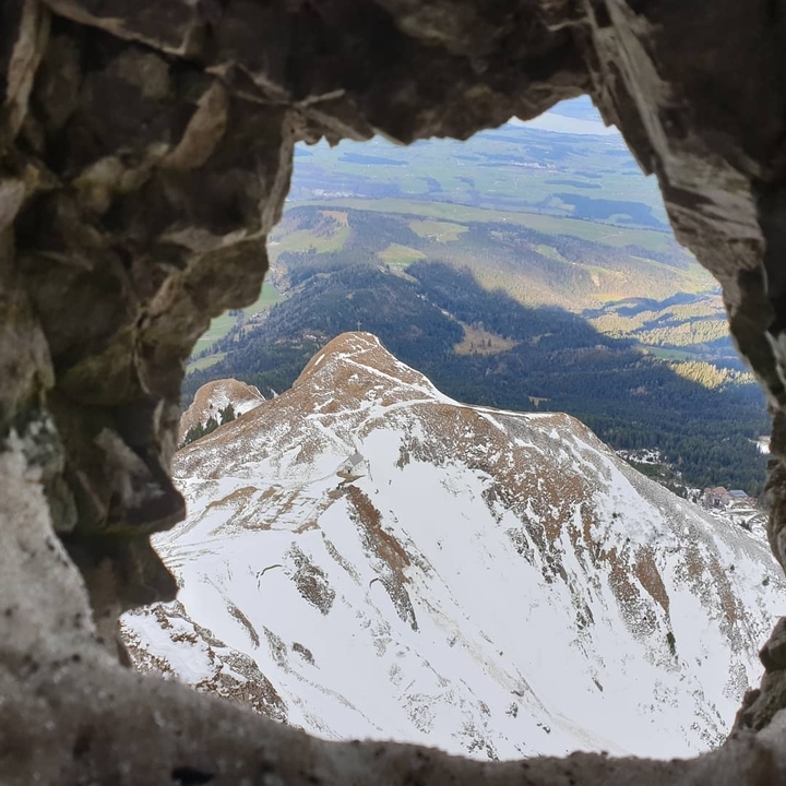 Snow-covered mountain peak viewed through a rocky opening