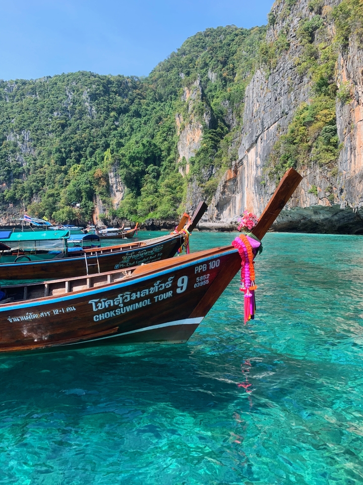 Decorated longtail boats in crystal-clear water.
