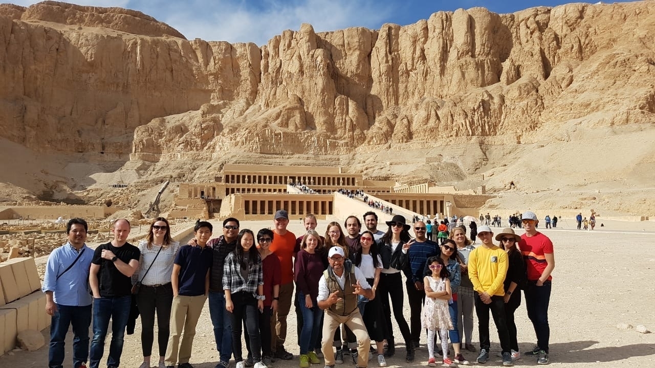 Groupe de touristes debout devant un temple ancien.