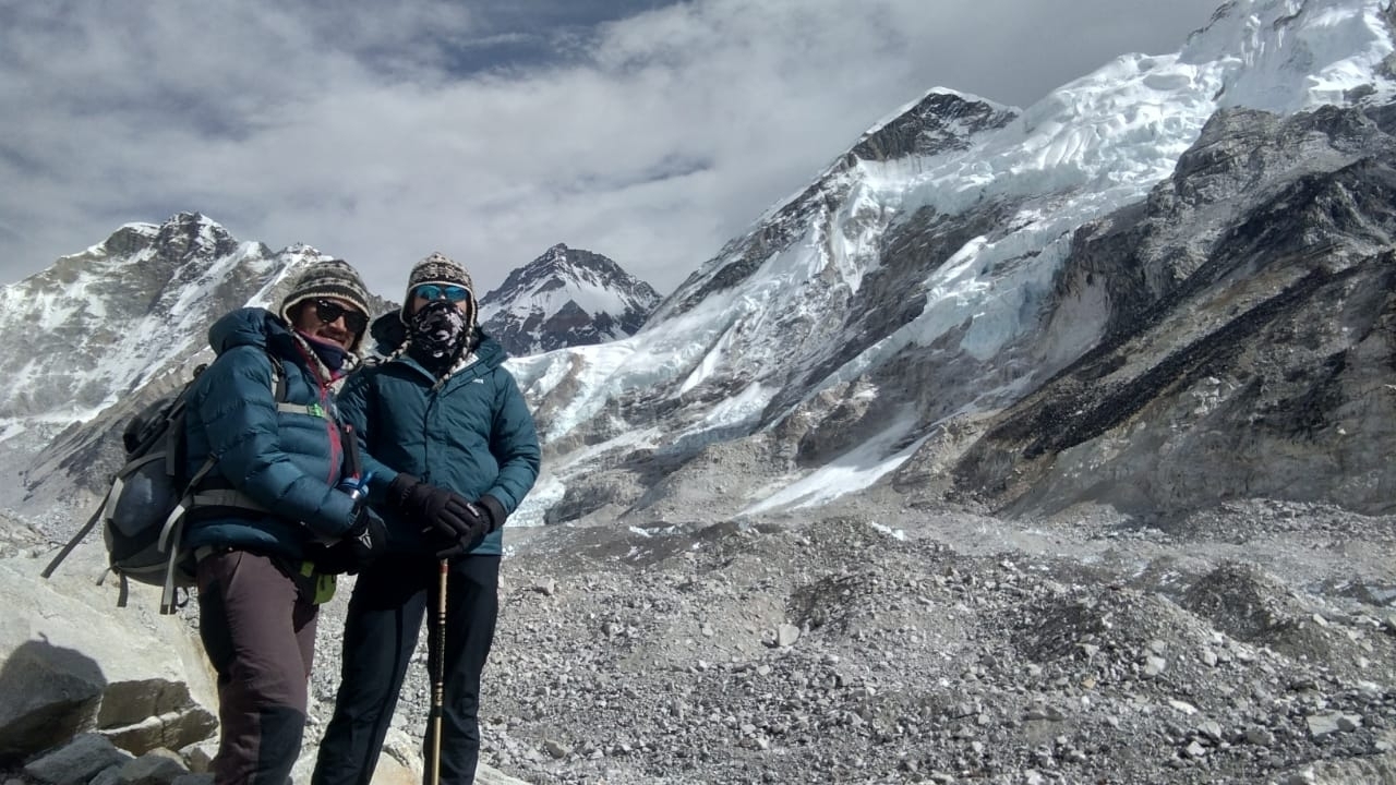 Two hikers posing in front of snowy mountain peaks.