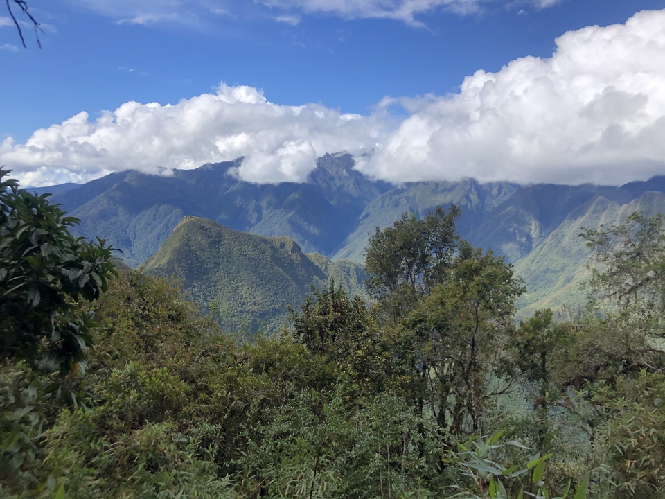 Paysage montagneux majestueux avec des nuages et un ciel bleu.