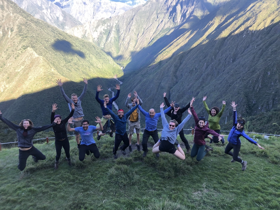 Groupe de personnes sautant de joie dans un paysage montagneux.