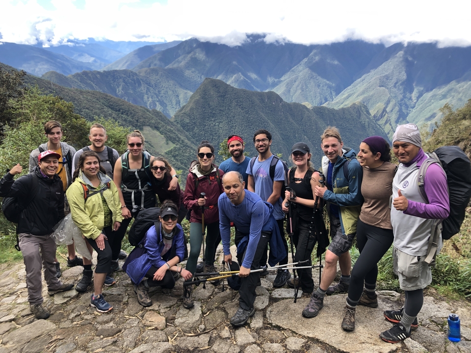 Groupe de randonneurs posant sur un sentier de montagne, entourés de sommets.