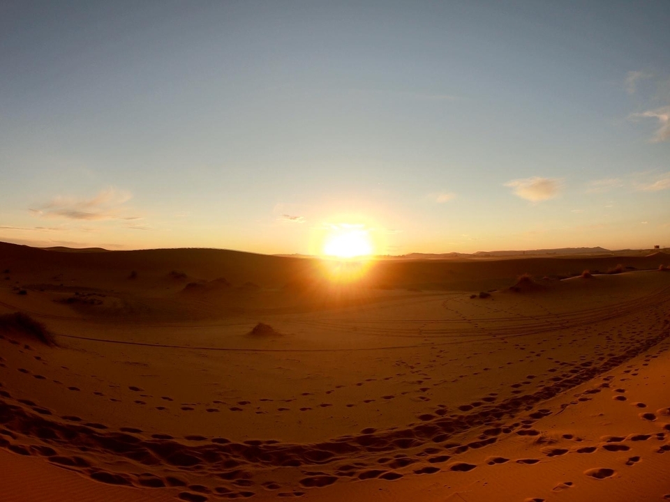 Vast desert landscape at sunrise with footprints in the sand.