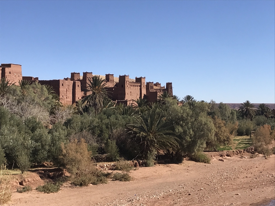 Ait Benhaddou with palm trees in the foreground.