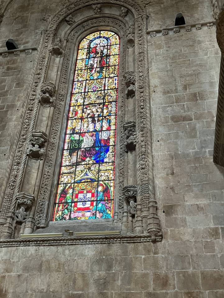 Stained glass window in a stone building, with colorful designs.