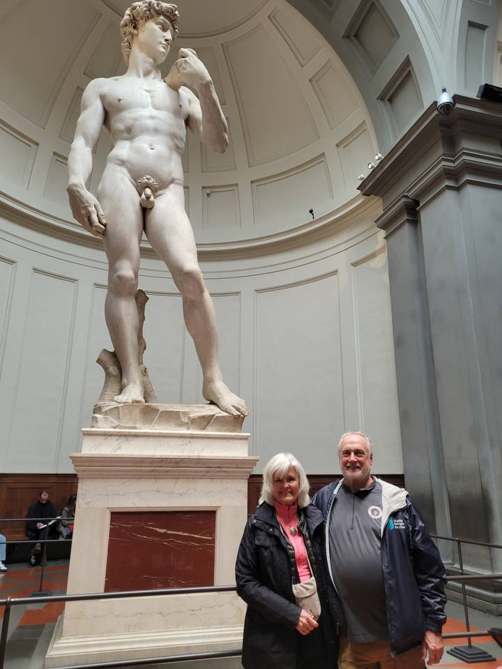Deux personnes posant devant une statue célèbre à l'intérieur d'un musée.