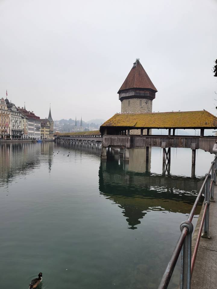 Pont couvert historique en bois au-dessus d'une rivière calme.