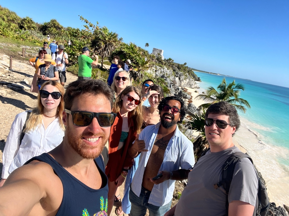 Group of friends posing on a beach with ruins and ocean view.