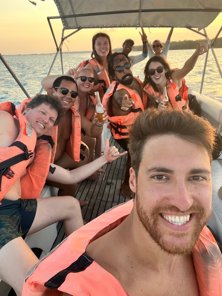 Group of friends on a boat wearing life vests and holding drinks.