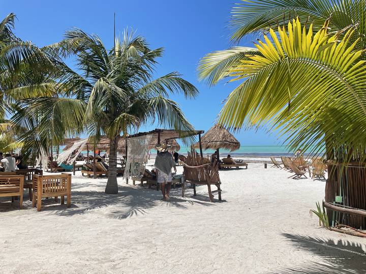 Beach setup with chairs and umbrellas under blue skies.