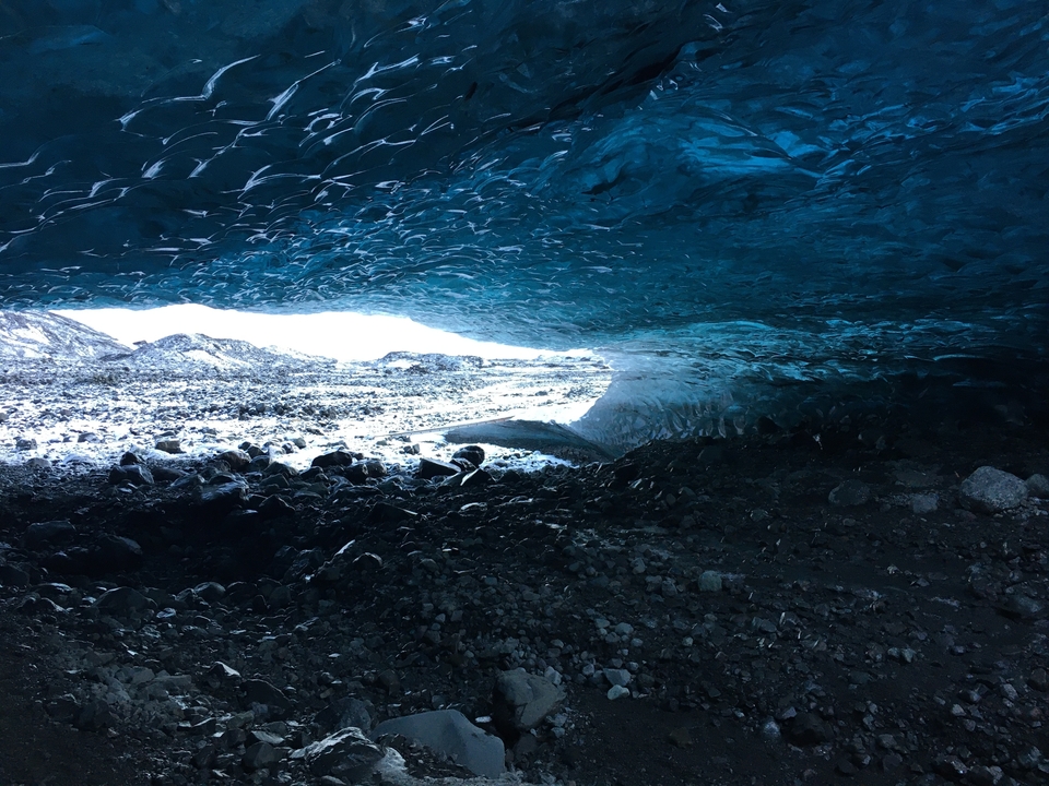 Inside an ice cave showing a view to the outside.