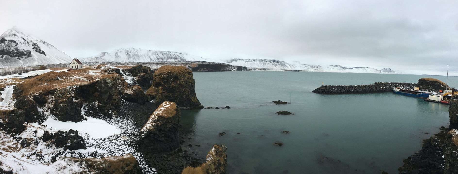 A coastal landscape with rocky shores and mountains in the background.