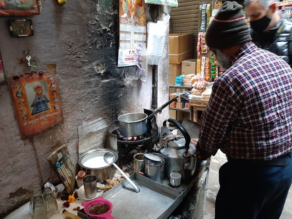 Homme préparant du thé chai dans un cadre rustique avec des condiments.