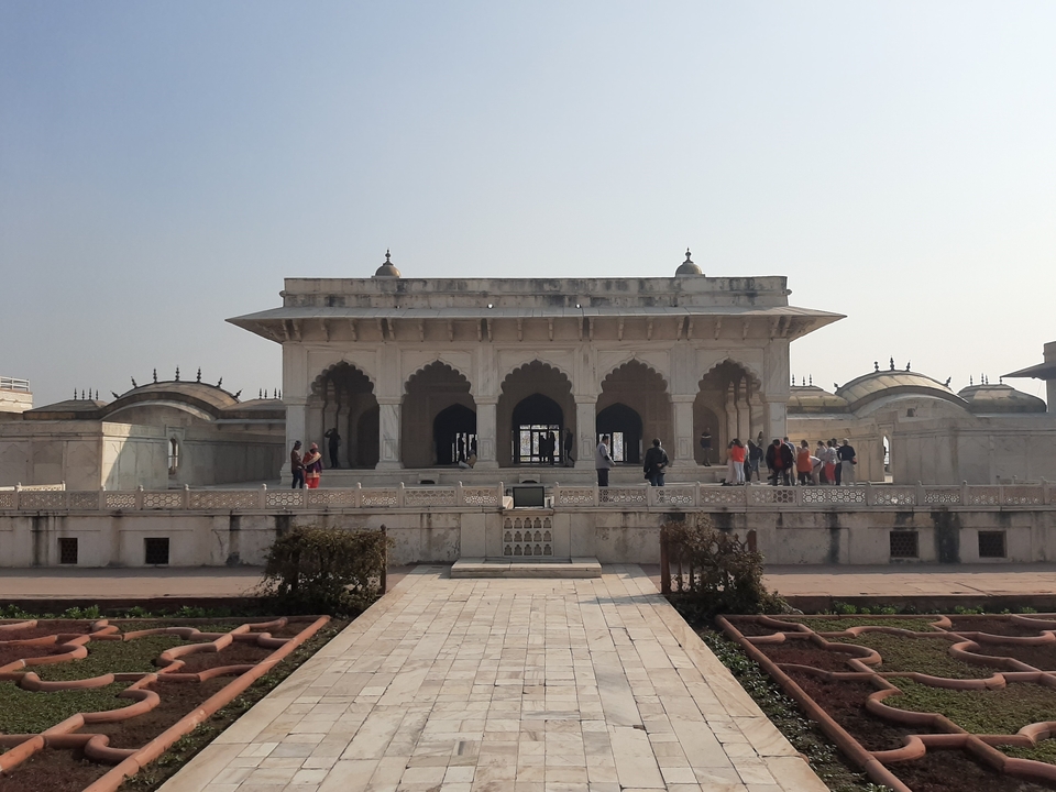 Visiteurs à la structure historique en marbre blanc dans le jardin.