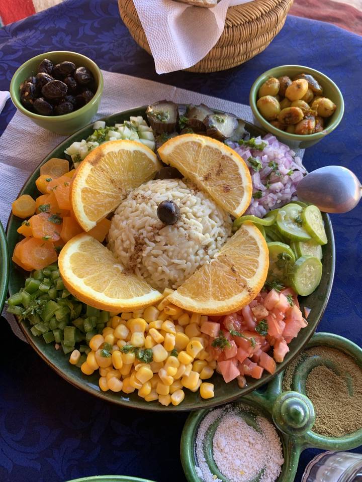 Een kleurrijke schotel met rijst, groenten en fruitschijfjes.