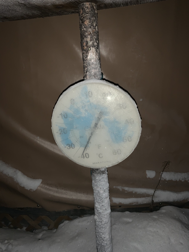 A frost-covered outdoor thermometer showing a very low temperature.