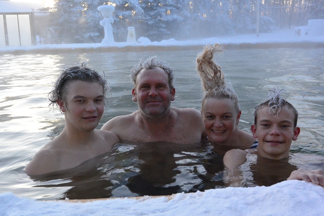 Family relaxing in a hot spring pool in winter.