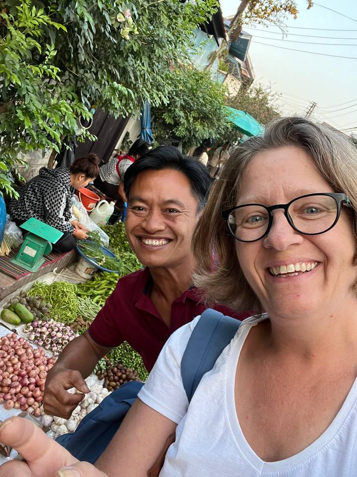 Deux personnes souriantes au milieu d'une scène de marché animé