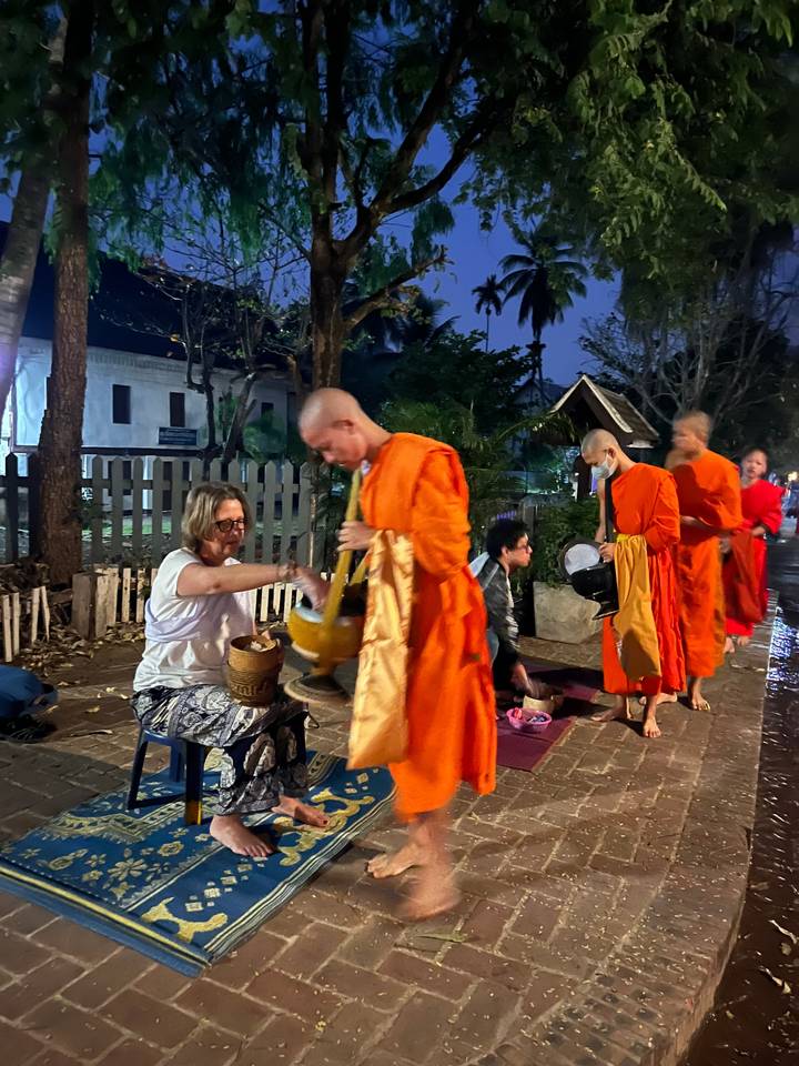 Moines en robes orange recevant l'aumône d'une personne assise