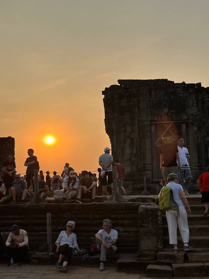 Foule de gens rassemblée dans un temple au coucher du soleil