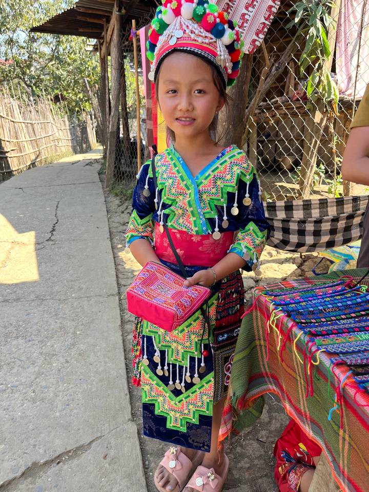 Personne en tenue traditionnelle colorée avec des motifs complexes et des accessoires.