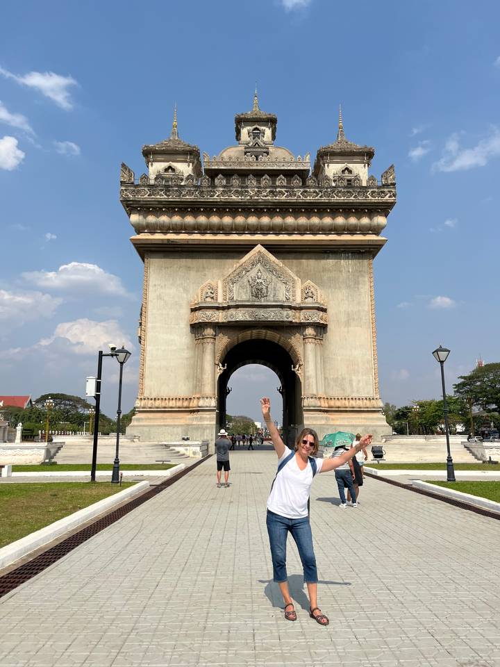 Individu posant devant une grande porte ressemblant au Patuxai à Vientiane.