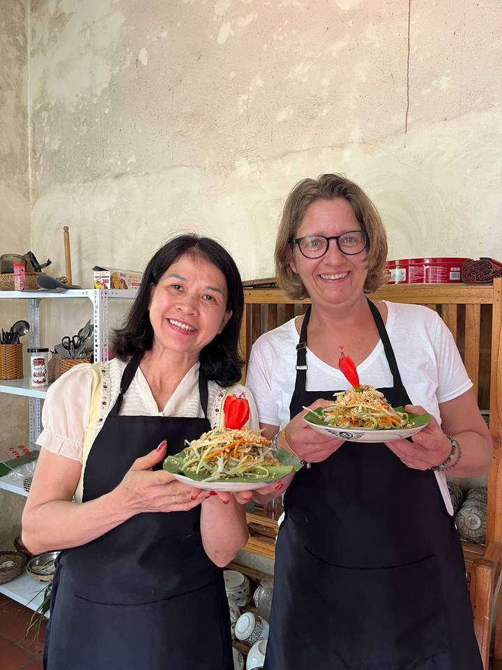 Deux personnes tenant des assiettes de plats culinaires, probablement d'un cours de cuisine.