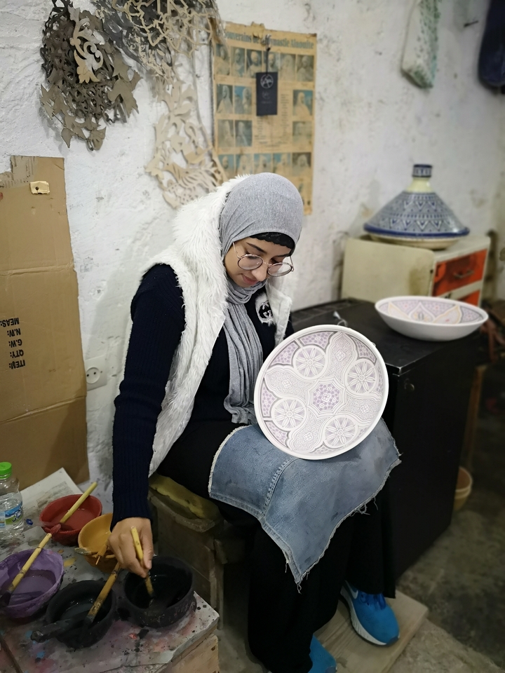 Person inspecting hand-painted ceramic plate.
