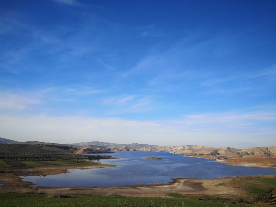 Lake with mountain view under a blue sky.