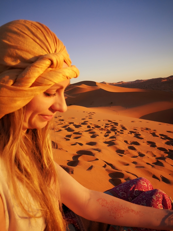 Close-up of a person with a sandy desert background.