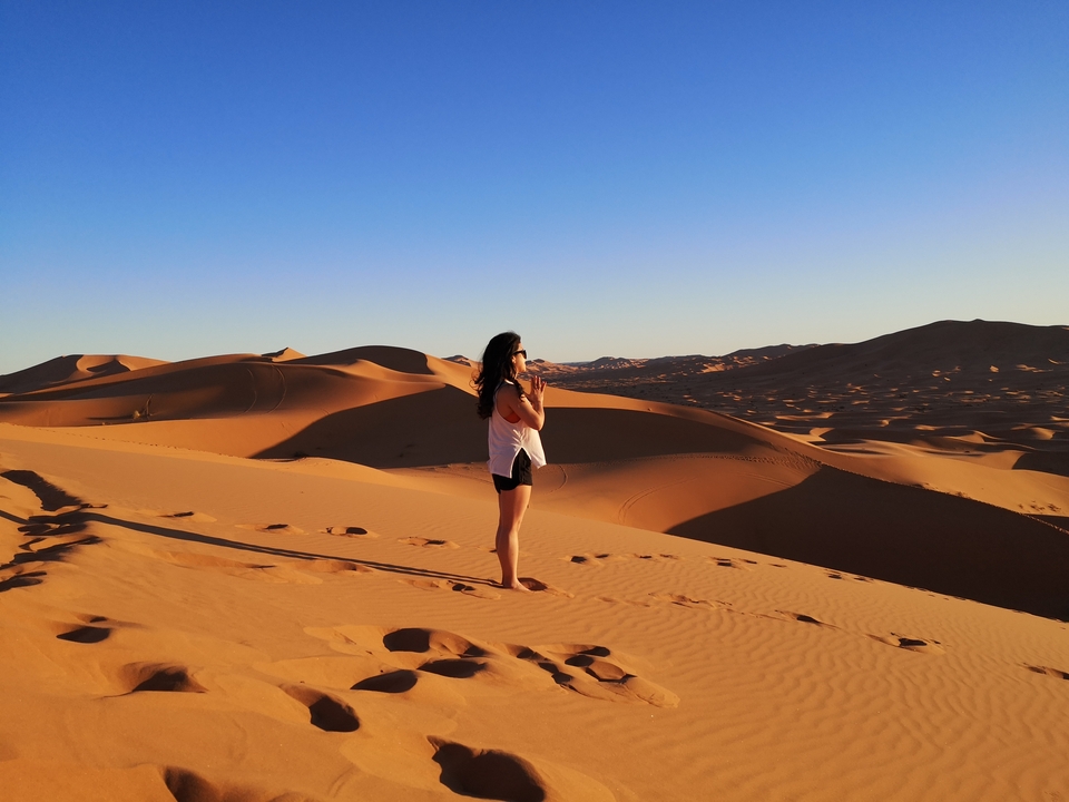 Person standing in a desert landscape with dunes.