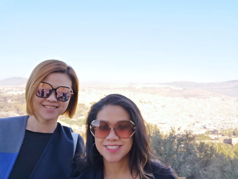 Two people taking a selfie with a city view.